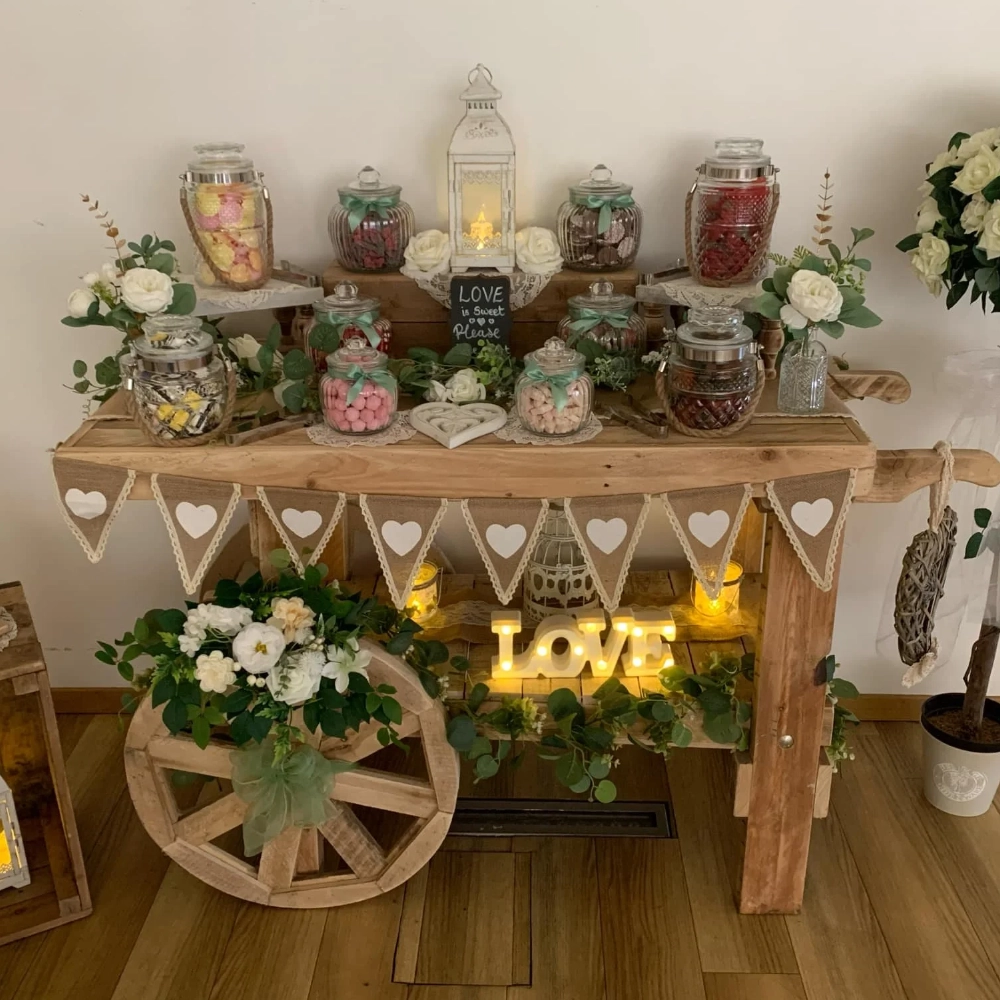 Rustic wedding sweet cart decorated with flowers, bunting, sweet jars and illuminated LOVE letters.