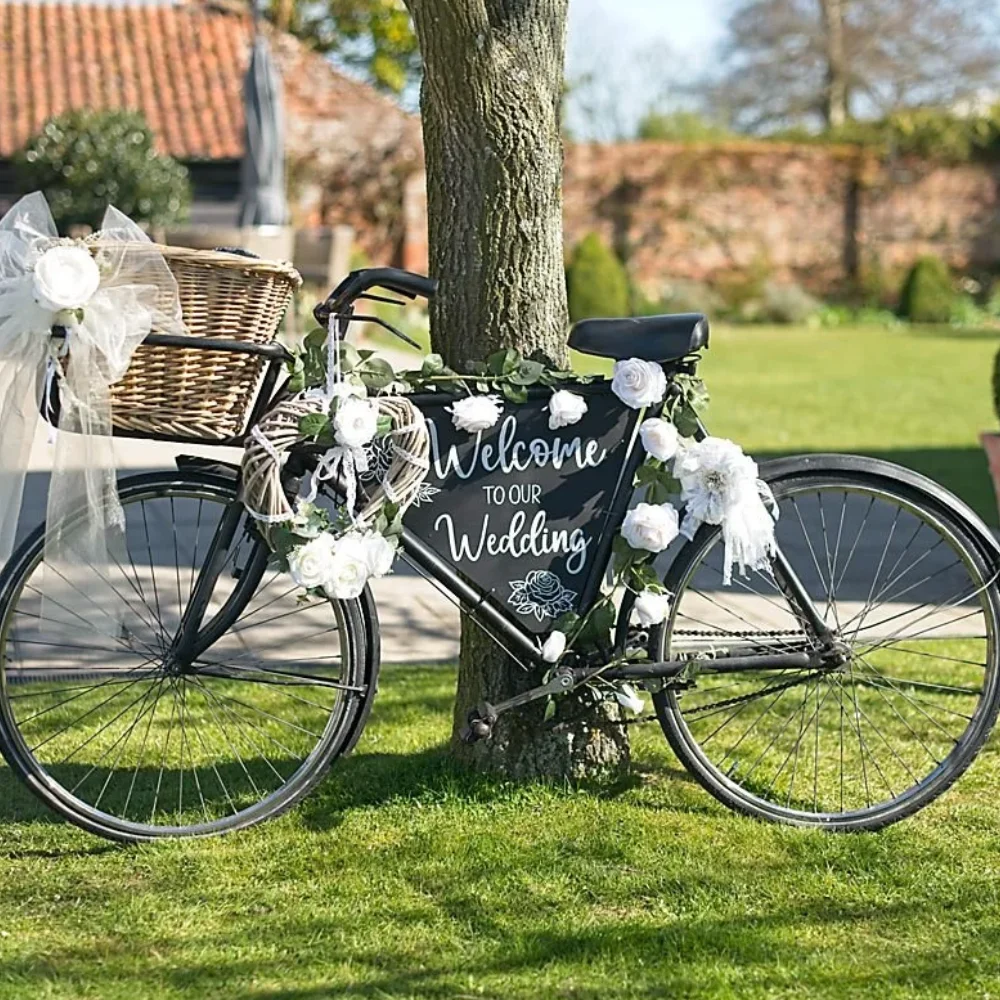 Vintage bicycle decorated with white flowers and a “Welcome to Our Wedding” sign at an outdoor wedding venue.